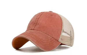 Close-up of rust-red washed cotton fabric and breathable beige mesh on a trucker hat