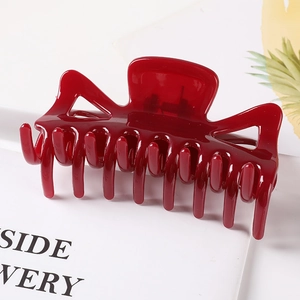 Macro detail of large burgundy hair claw clip with glossy geometric design and hollow structure