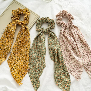 Detail view of floral ponytail scrunchies in yellow green and beige chiffon material