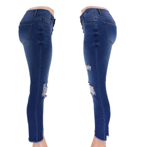 Detail view of high waist blue ripped denim jeans with distressed knees and frayed hems