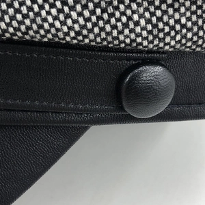 Detail of tweed fabric texture and black leather strap with covered button on octagonal hat