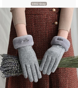 Close-up of gray winter gloves with faux fur trim and elegant embroidery detailing
