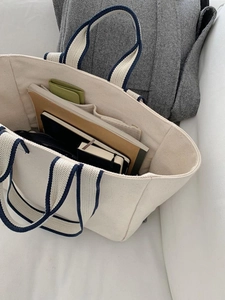 Top view of beige canvas tote bag interior with blue handles and organized personal items