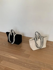 Detail of minimalist canvas tote bags in black and cream white with striped handles