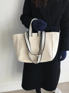 Close-up of minimalist canvas tote bag with navy blue strap detailing and texture