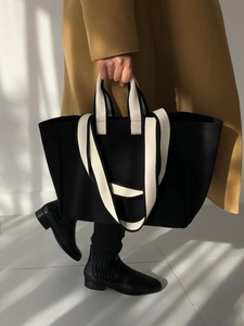 Detail of black canvas tote bag with contrast white handles and minimalist texture
