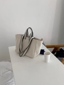 Detail of off-white canvas tote bag with black double handles for hand or shoulder carry