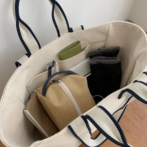 Spacious off-white canvas tote bag with blue striped handles showing large inner capacity