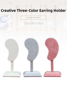 Three velvet ear-shaped earring display stands in white, grey, and pink colors