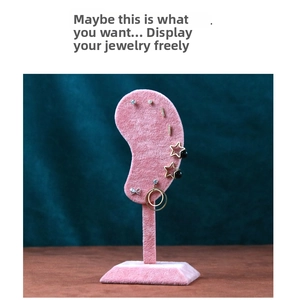 Pink velvet ear-shaped jewelry stand showcasing multiple gold earrings and studs