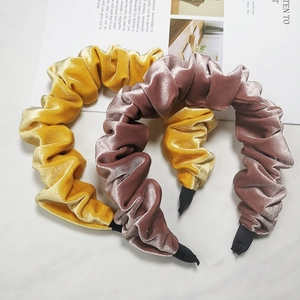 Velvet pleated headbands in yellow and pink brown colors on marble surface