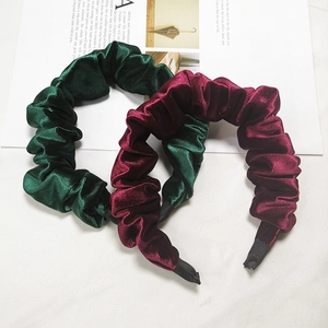 Pleated velvet headbands in dark green and burgundy on a white background with a magazine