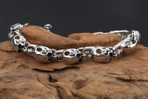 Detailed close-up of a punk style skull link bracelet displayed on a driftwood piece