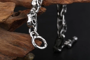 Macro shot of silver skull link bracelet with T-bar clasp on textured wood base