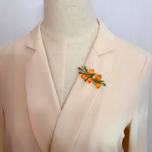 Vintage style orange glass berry brooch pinned on a beige blazer for a natural floral look