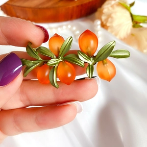 Detailed macro view of olive branch hair clip with green leaves and orange frosted beads