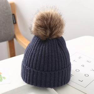 Detalle de textura de punto acanalado azul marino y pompón de piel sintética en gorro de bebé