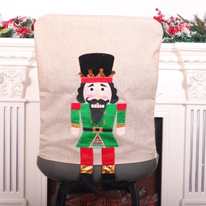 Nutcracker Christmas chair cover made of linen fabric shown on a dining chair by the fireplace
