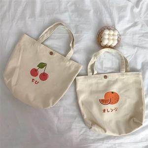 Detailansicht der Canvas-Lunchbags mit Kirsch- und Orangendruck und Metalldruckknopf