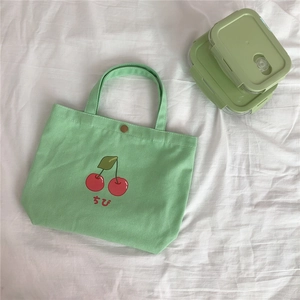 Detail der hellgrünen Canvas-Lunchtasche mit Kirschdruck und Metalldruckknopf-Verschluss