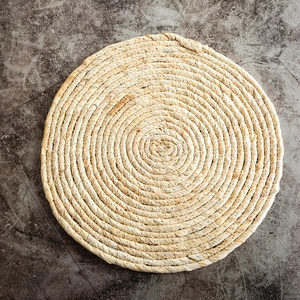 Dettaglio macro della trama intrecciata a spirale di una tovaglietta di paglia