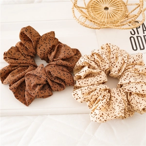 Flat lay of brown and beige polka dot fabric scrunchies on a white surface with props