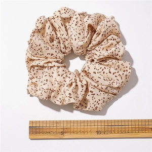 Oversized beige hair scrunchie with brown polka dots and elastic fabric texture