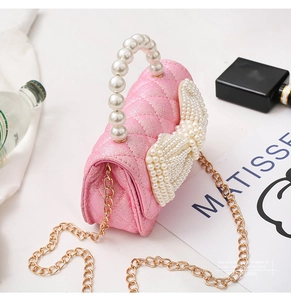 Detail of pink quilted mini bag with pearl bow decoration and gold chain strap