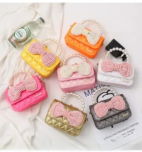 Detail of colorful mini girls' crossbody bags with pearl bows and glitter finish