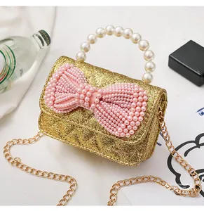 Detail of gold sequin mini bag featuring pink pearl bow and luxury quilted texture