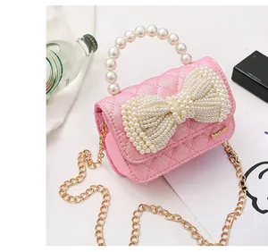 Close-up of pink mini bag with quilted glitter texture, pearl bow and gold chain strap