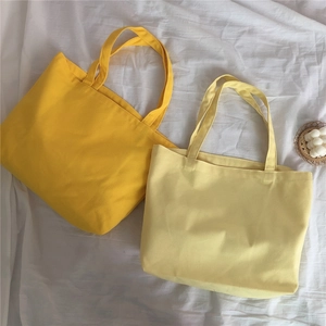 Λεπτομέρεια flat lay από κίτρινες και μπεζ υφασμάτινες τσάντες σε λευκό λινό ύφασμα