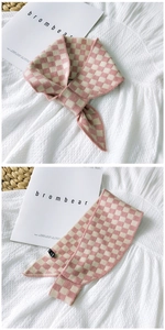 Detail of pink and beige checkerboard knit scarf with soft texture and small black label