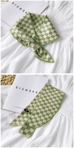 Detail of green and white checkerboard knit scarf with soft texture and flat edges