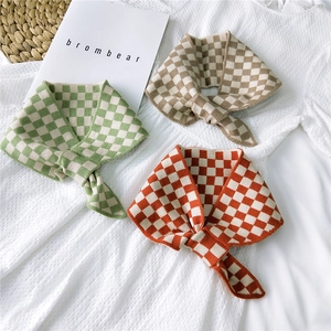 Three checkered knit scarves in green, brown, and orange displayed on a textured background