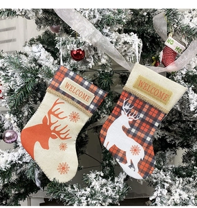 Detail of linen Christmas stockings with reindeer silhouette and WELCOME text on a tree