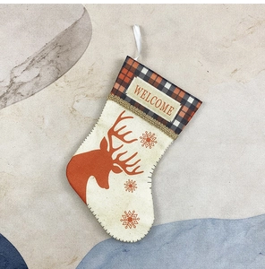 Detail of burlap Christmas stocking featuring orange reindeer, snowflakes and Welcome tag