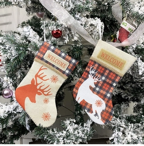 Detail of linen Christmas stockings with reindeer patterns hanging on a decorated tree