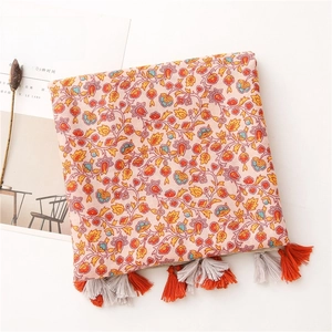 Detail of floral printed bohemian cotton shawl with orange and grey tassel fringe trim