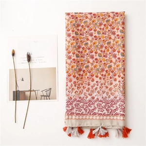 Detail of floral patterns and fringe on an orange-red cotton linen shawl with props