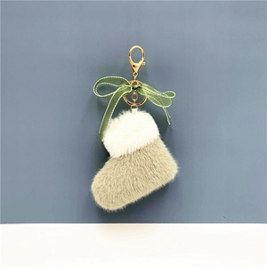 Detail of plush Christmas boot keychain with green ribbon bow and gold metal ring