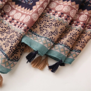 Detail view of ethnic floral patterns and tassel trim on a cotton linen sun shawl