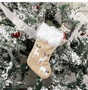 Detail of beige linen Christmas stocking with white reindeer and faux fur hanging on tree