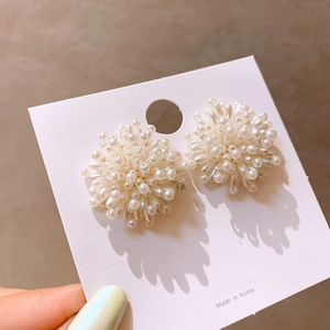 Elegante weiße Perlenohrringe im Feuerwerk-Design mit edlem Perlmuttglanz in der Hand
