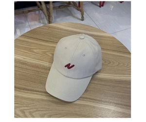 Vue de dessus d'une casquette de baseball en coton beige avec broderie N rouge sur bois