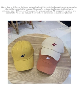 Détail de trois casquettes de baseball en coton avec broderie N en jaune, beige et brique