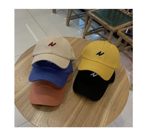 Vue de dessus de cinq casquettes de baseball colorées avec broderie N sur table en bois