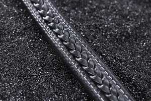 Close-up of black braided leather strap with detailed white edge stitching texture