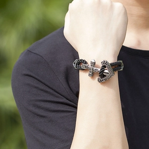Men's braided leather rope bracelet with punk anchor skull clasp on wrist in nature