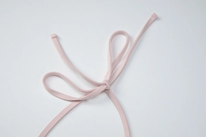 Macro detail of a light pink halter tie with high-quality stitching on elastic fabric